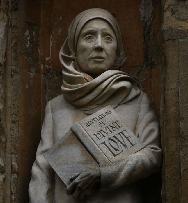 AN IMAGE OF A STATUE OF JULIAN OF NORWICH, AT NORWICH CATHEDRAL. SHE IS HOLDING A COPY OF HER BOOK, REVELATIONS OF DIVINE LOVE